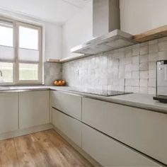 a kitchen with wooden floors and white walls, has a microwave on the counter next to the window