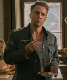 a man in uniform holding a plate with food on it