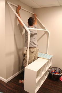 a man standing on top of a stair case in a room with hard wood flooring