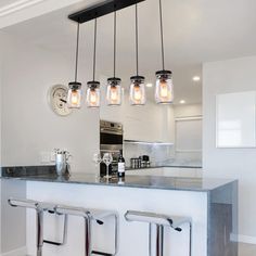 a kitchen island with four hanging lights over it