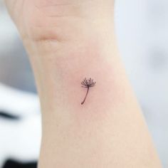 a small tattoo on the ankle of a woman's left arm with a single flower