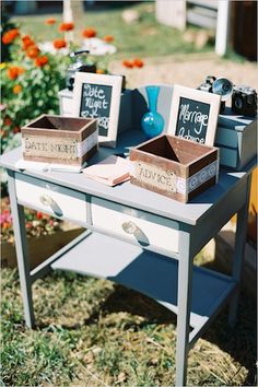 two wooden boxes sitting on top of a table with flowers in the backgroud