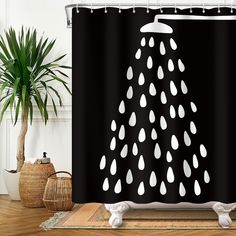 a shower curtain with black and white rain drops on it next to a potted plant