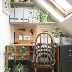 a desk with a chair and some plants on it in a room that has a slanted roof