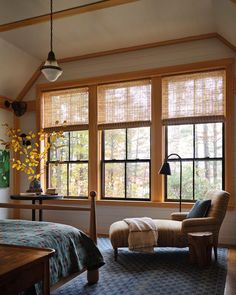 a bed room with a neatly made bed next to two large windows and a chair