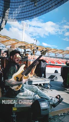 a man sitting on top of a chair holding a guitar