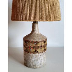 a lamp that is sitting on top of a table next to a light fixture with a woven shade over it