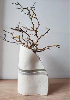 a white vase with branches in it on a table