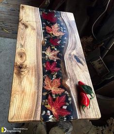 a piece of wood that has been painted with autumn leaves and red peppers on it