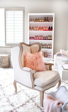 a white chair sitting on top of a rug next to a shoe rack filled with shoes