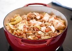 a red pot filled with food sitting on top of a stove