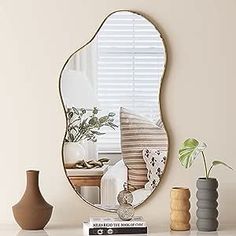 a mirror sitting on top of a white table next to vases and a potted plant