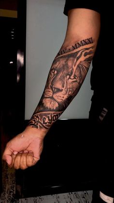 a man's arm with a lion tattoo on it and his hand in the air