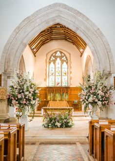 the inside of a church with pews and flowers in vases on each side