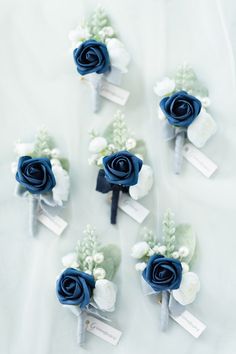 blue and white boutonnieres are arranged on a bed sheet with name tags