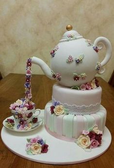 a three tiered cake decorated with flowers and a teapot