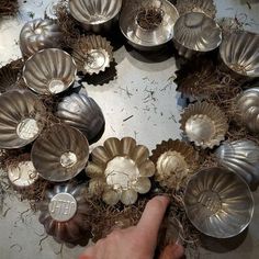 a person pointing at some metal objects in the middle of a wreath made out of seashells