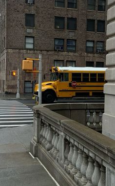 a yellow school bus driving down a street next to tall buildings