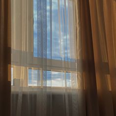 an open window with sheer curtains and blue sky in the background