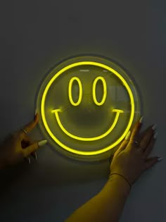 a woman's hands holding up a neon smiley face