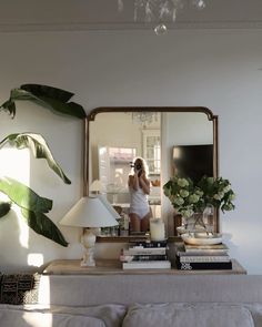 a woman taking a selfie in front of a mirror with books on the table