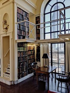 a living room filled with lots of furniture and bookshelves next to a window