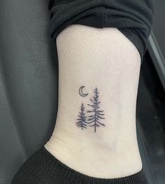 a small pine tree tattoo on the side of the ankle, with a crescent moon above it