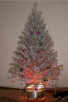 a small white christmas tree sitting on top of a wooden floor next to a wall