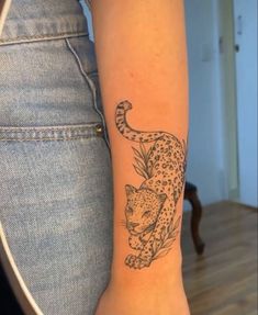 a woman's arm with a tattoo of a cheetah and leaves on it