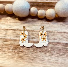 a pair of white and gold earrings sitting on top of a wooden table