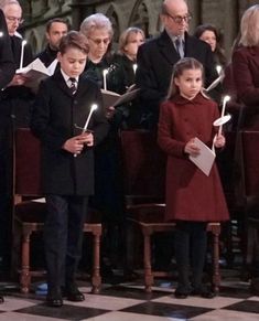 a group of people standing next to each other in front of choirs holding lit candles