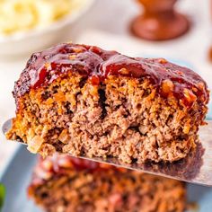 a piece of meatloaf is being held up by a spatula with sauce on it