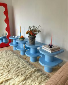 a blue table sitting on top of a wooden floor next to a mirror and vase filled with flowers