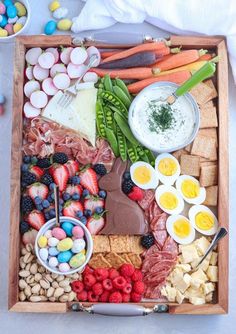 Easter charcuterie board with vegies, crackersm cheese and candy on a wooden rectangular board. Easter Grazing Board, Easter Platter, Easter Deviled Eggs, Bunny Bread