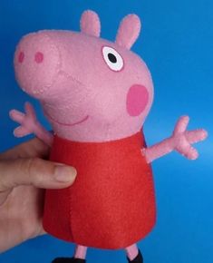 a hand holding a pink stuffed animal in a red dress