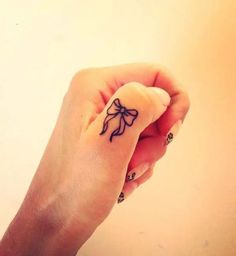 a woman's hand with a small bow tattoo on it