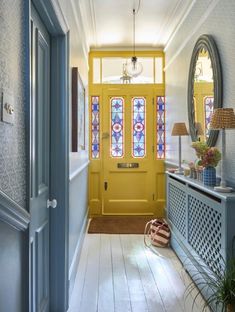 the hallway is painted bright yellow and has stained glass windows on either side of the door