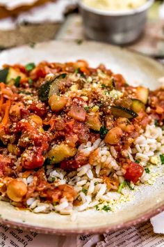 a white plate topped with rice covered in meat and veggies on top of a table