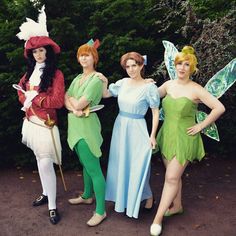 three women dressed as tinkerbells standing next to each other in front of trees