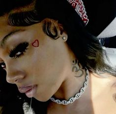 a close up of a person with tattoos on her face and neck, wearing a hat