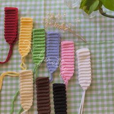 four crocheted utensils are lined up on a checkered tablecloth