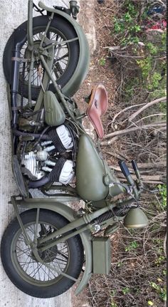 an old army motorcycle is parked on the side of a road in front of some trees