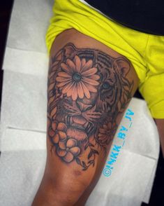 a person with a tiger tattoo on their leg and some flowers in the other hand