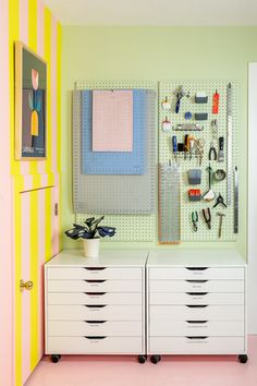 a room with two white drawers and pegboards on the wall next to each other