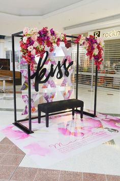 a bench in front of a display with flowers on it and the word bliss written below