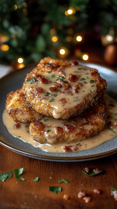 two meat patties covered in gravy on a plate next to a christmas tree