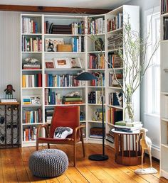 a living room filled with lots of books on top of a hard wood floor next to a window