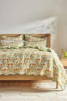 a bed with sunflowers and green trim on it in a white walled room