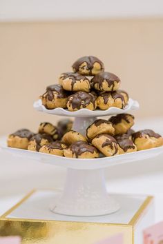 chocolate chip cookies stacked on top of each other on a white cake plate with gold trim