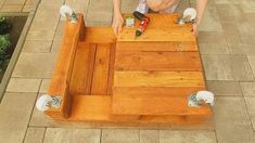 a man is working on a wooden table with two screwdrivers and one hammer